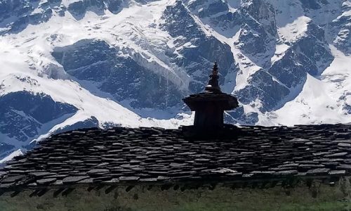 Trekker bestaunt die kleine Punggen Gompa auf dem Trek rund um den Manaslu, im Hintergrund das gewaltige Bergmassiv
